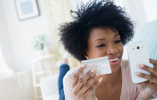 mulher segundo um cartao de credito e olhando para um celular
